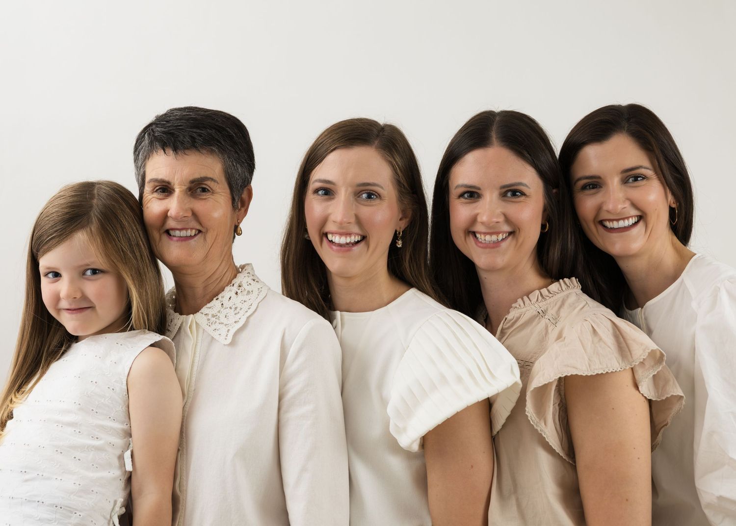 Group portrait of people wearing white clothing against a white backdrop.