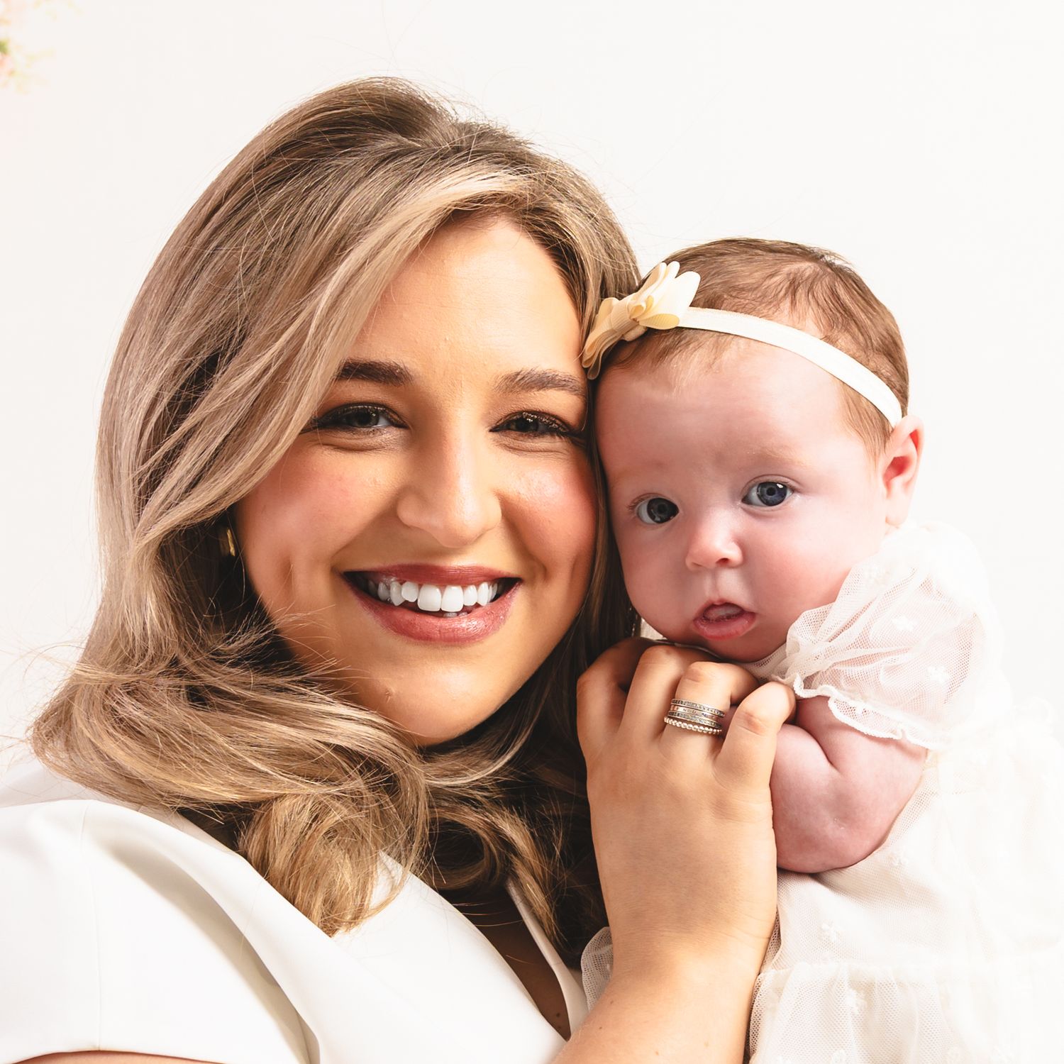 Mother and baby in white clothing share tender moments in a series of light, bright studio portraits.