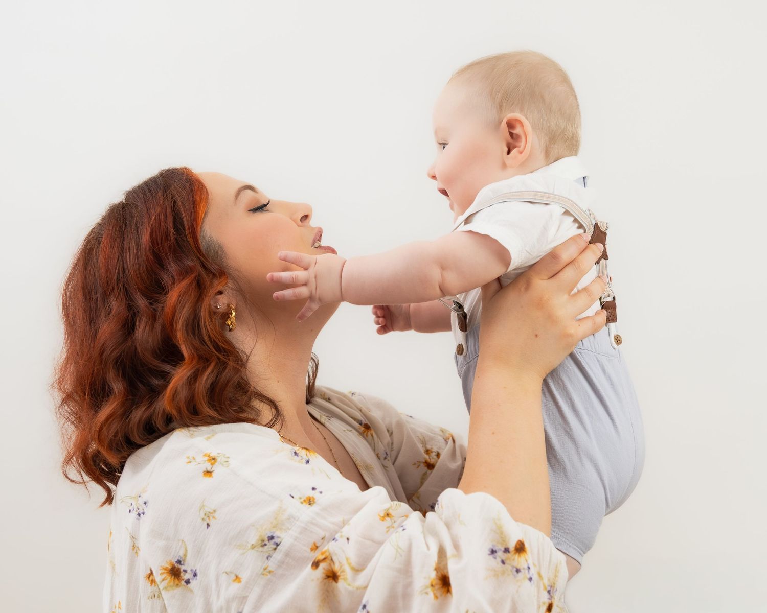 Parent and child sharing joyful moments against white studio backdrop.