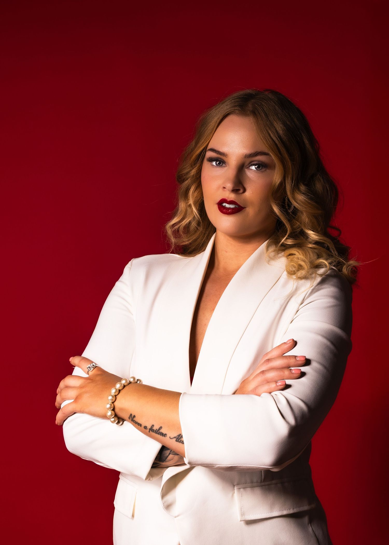 Professional studio portraits of someone in a white blazer against a deep red background showing different poses.