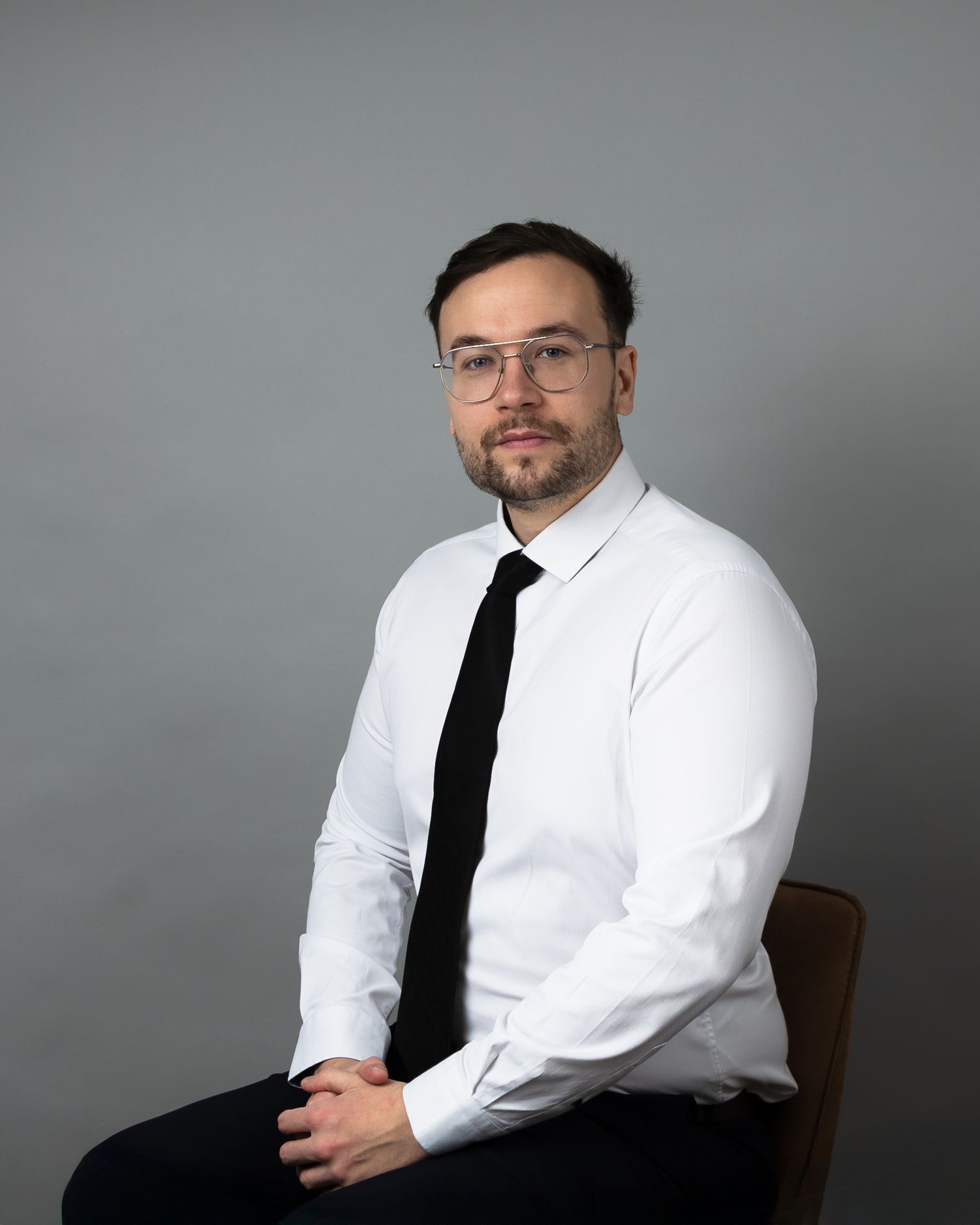 A series of professional headshots showing a person in a white dress shirt and black tie against a gray background.