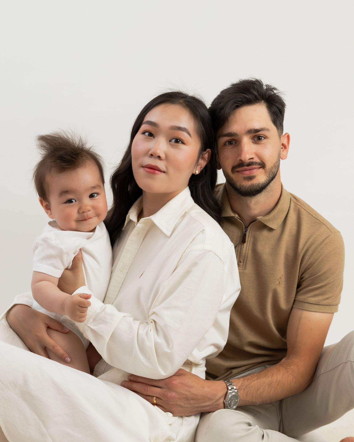 Modern family studio portraits with neutral tones and white backdrop.