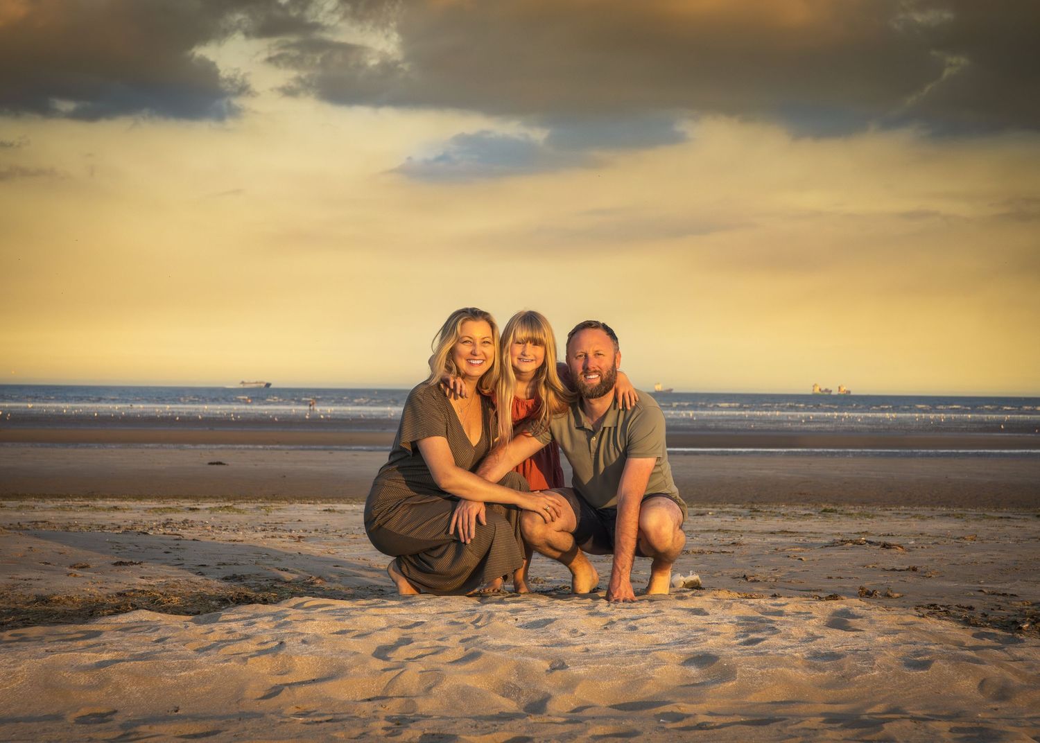 Beautiful beach sunset photography session with golden sky and sand dunes backdrop.