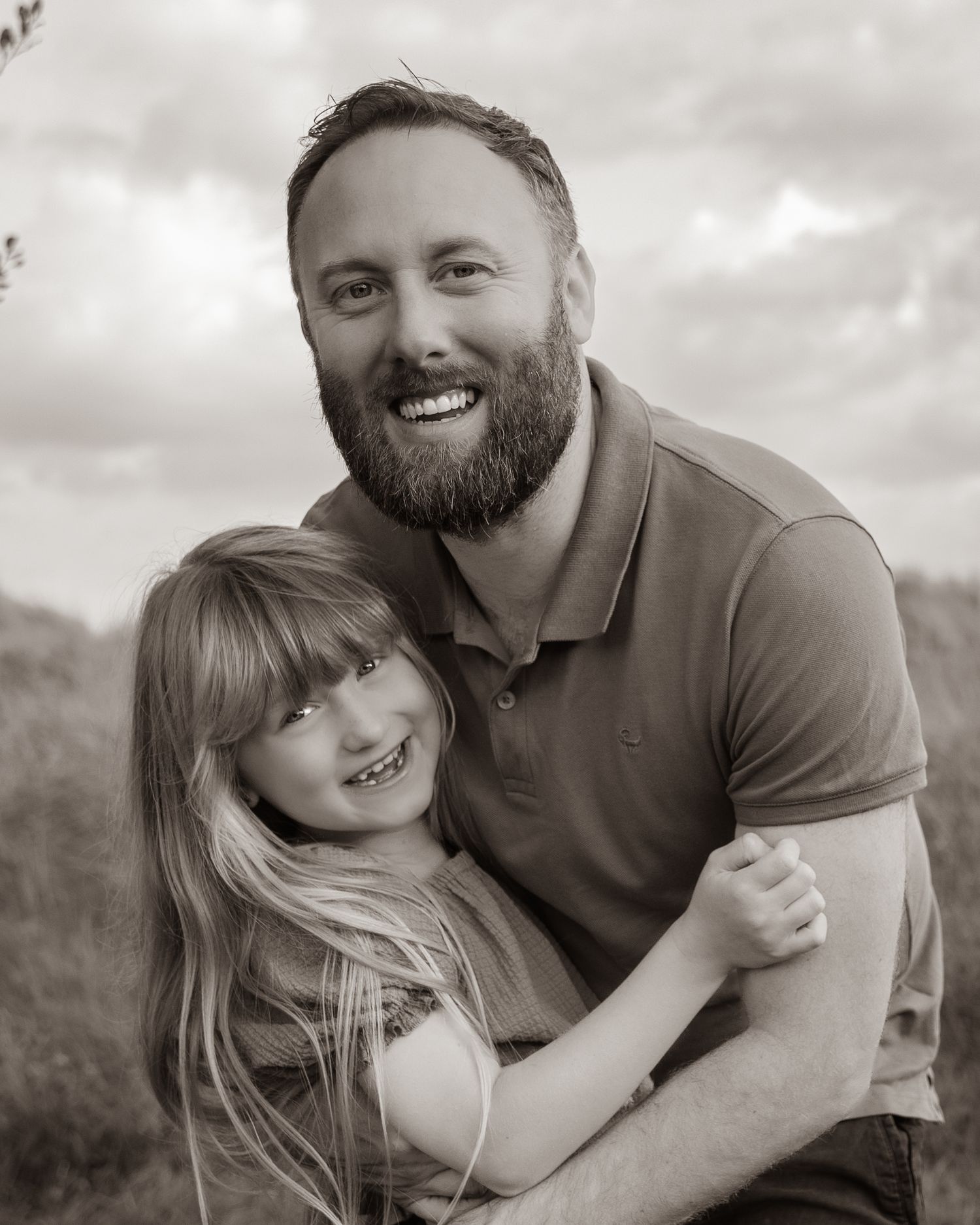 Black and white portrait of joyful family embracing outdoors.