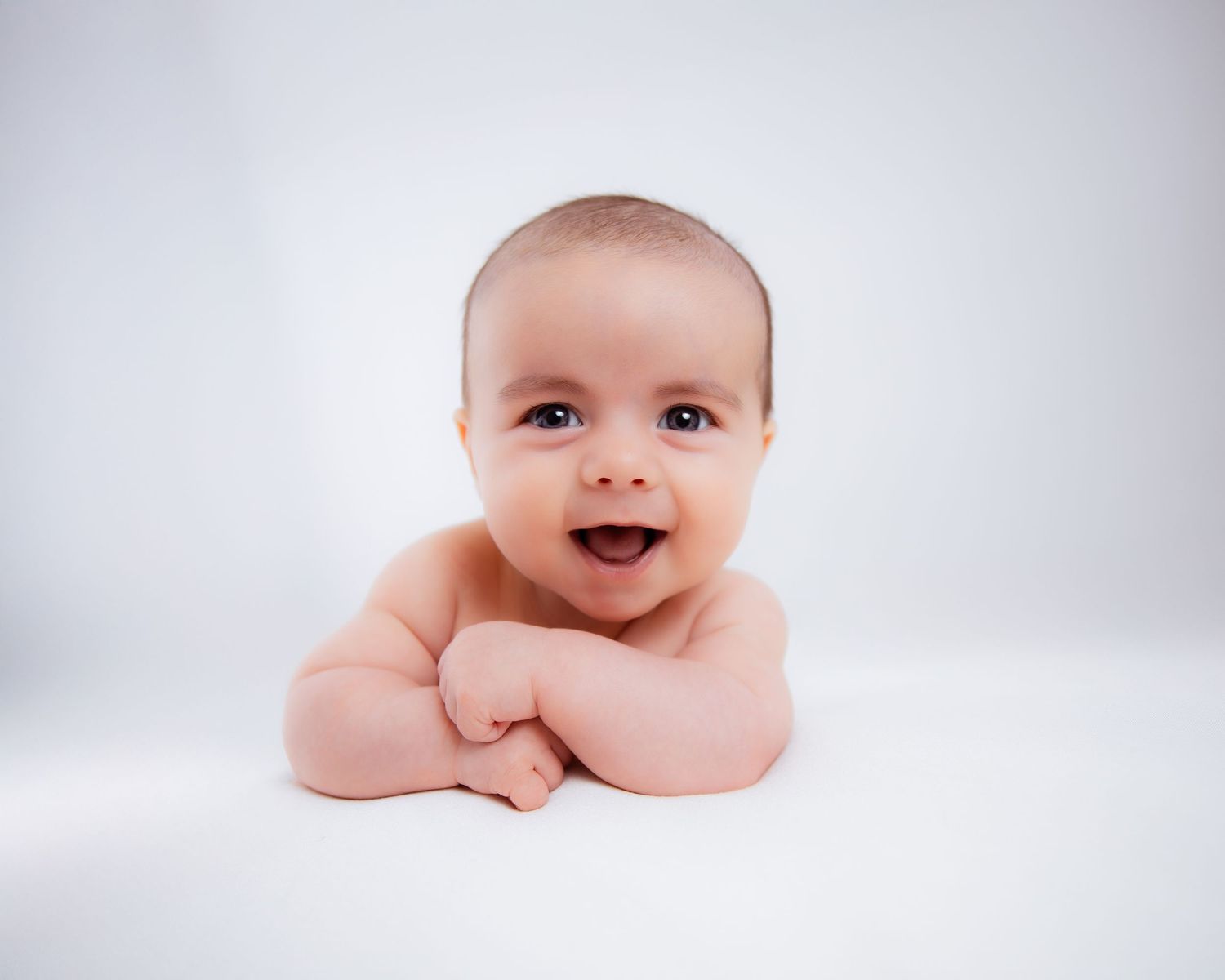 A series of black and white portraits showing different expressions and poses of a baby against a white background.