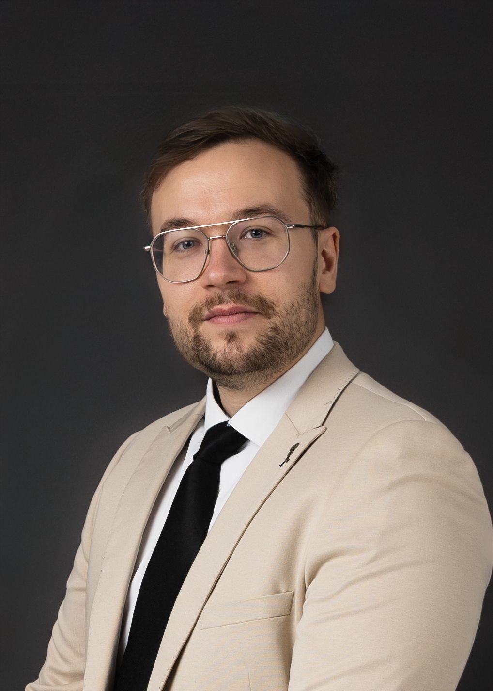 Professional studio portrait of someone in a cream suit and black tie against dark background showing different poses.