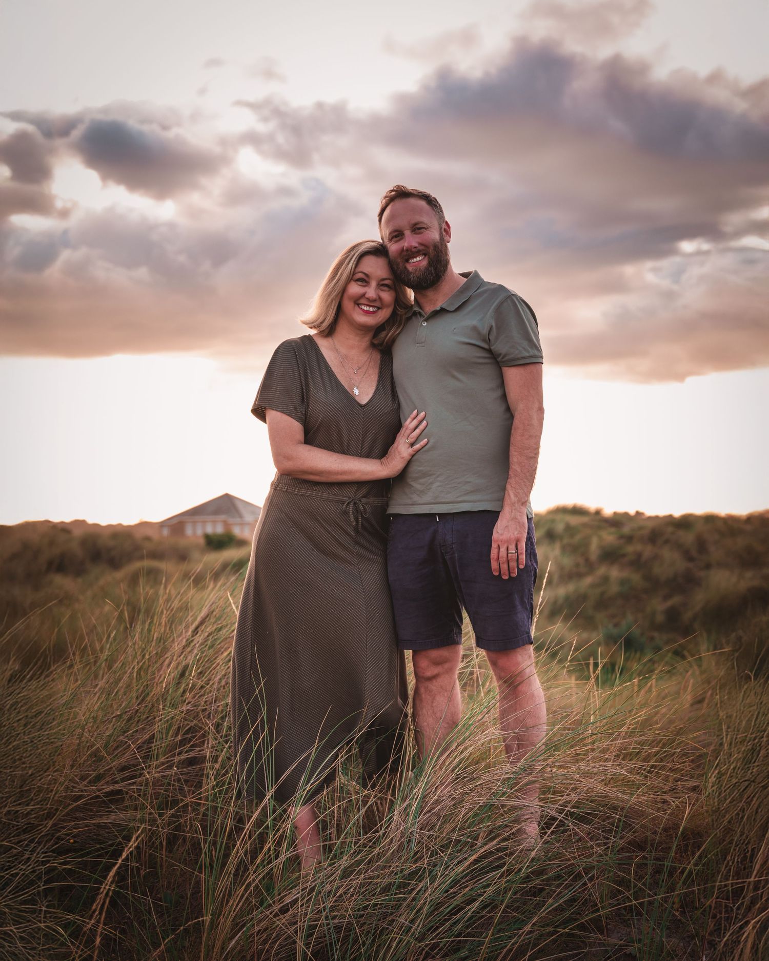 Romantic couple portrait session in coastal dunes during golden hour.