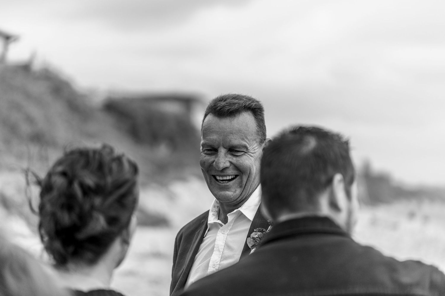 A joyful black and white moment captured during a beach wedding ceremony.