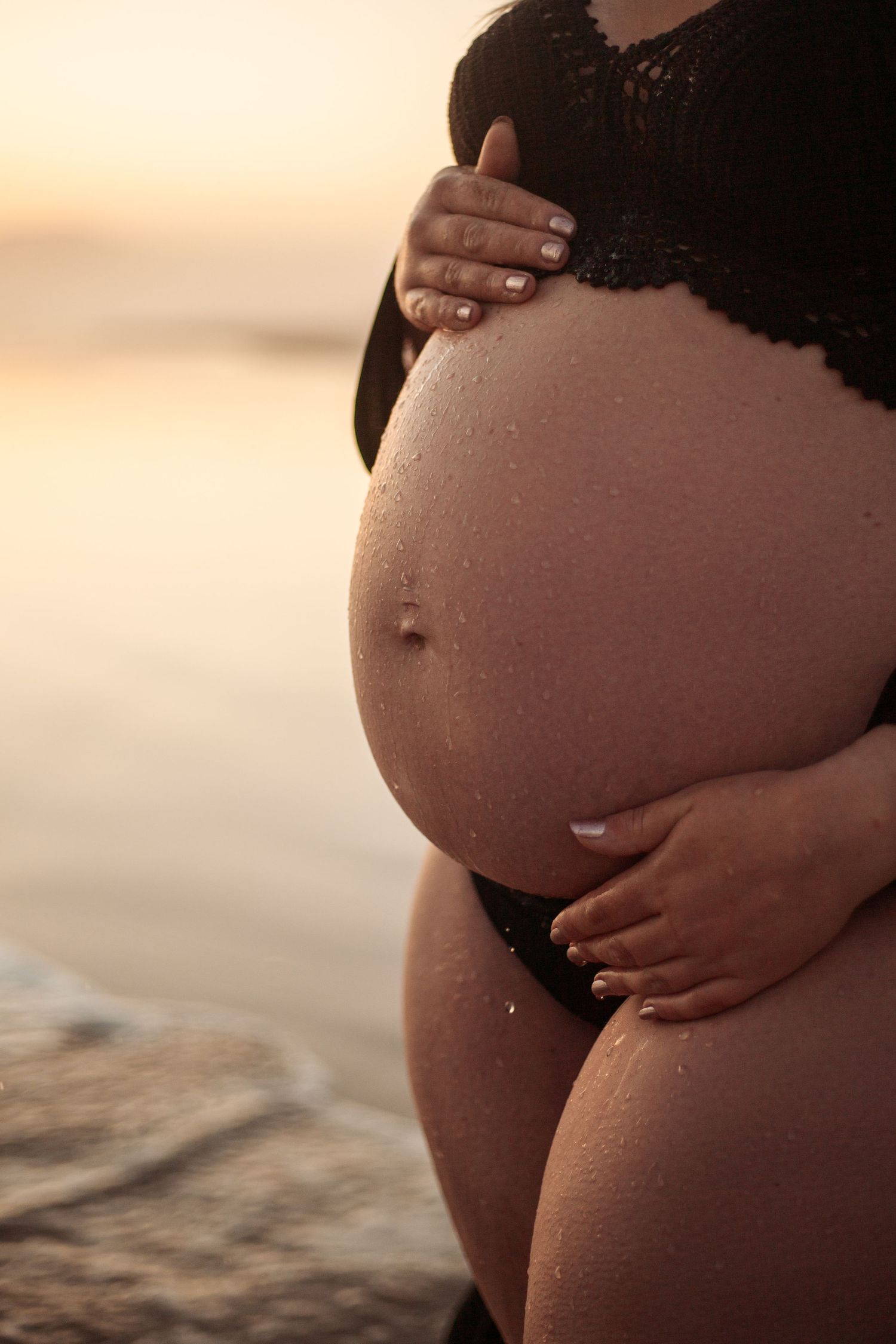 A series of silhouetted pregnant bellies photographed against a warm sunset background at the beach.