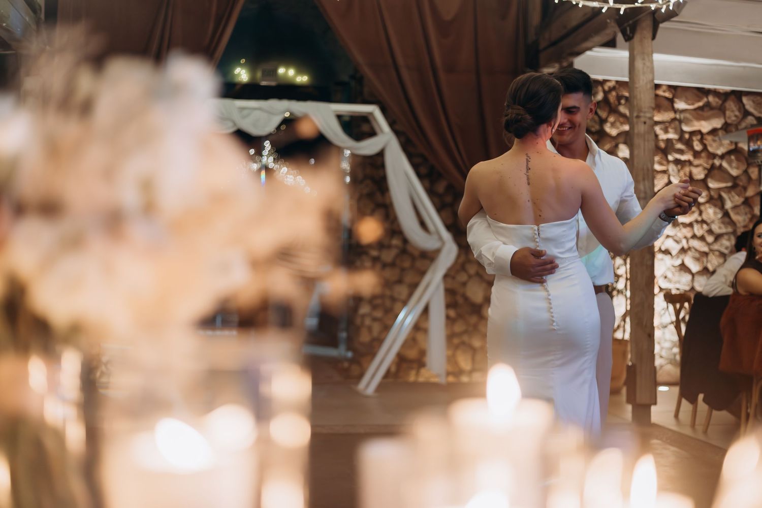 Bride and groom share a romantic first dance surrounded by glowing candles at an elegant wedding reception.