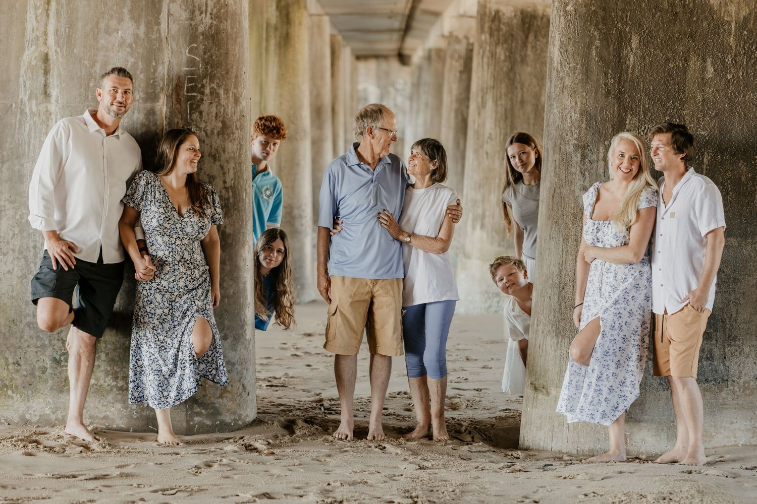 A series of family photos taken against a rustic stone wall backdrop in casual summer attire.