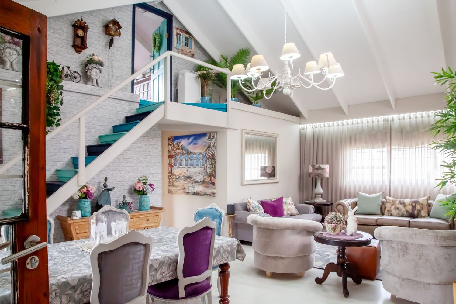 Modern coastal living room features white and gray decor with natural light, houseplants, and beachy accents.