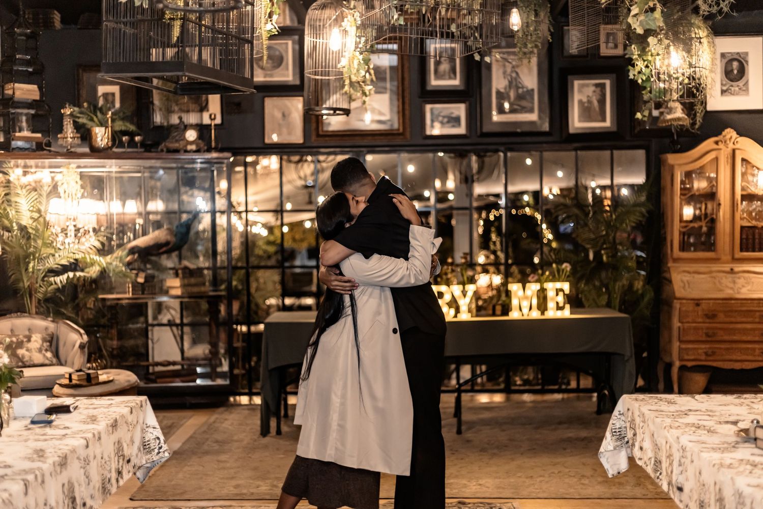 A romantic evening wedding reception setup with glowing string lights and elegant table settings in a rustic outdoor venue.