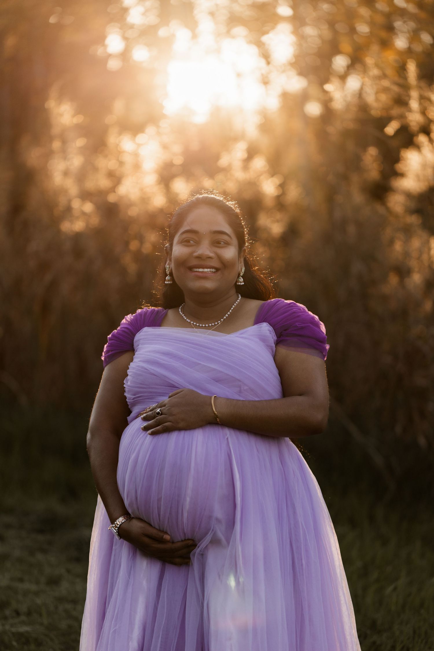 A person in a flowing lavender dress poses outdoors during golden hour sunset in a series of four photos.