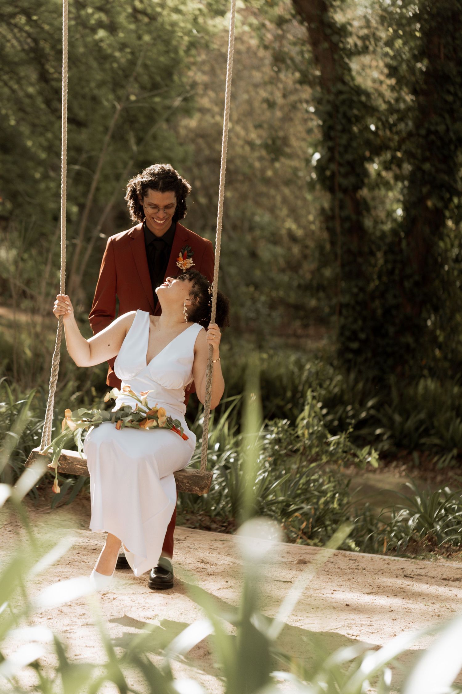 A romantic couple enjoying a peaceful moment together on a wooden swing in a sunlit garden setting.