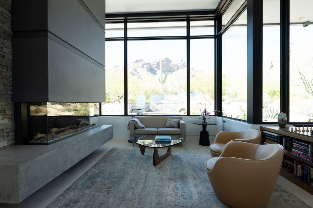 Contemporary living space with tan leather chairs and expansive desert landscape views.