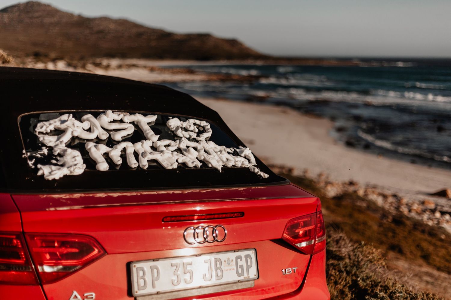A collage of scenic coastal views featuring a red Audi car parked near a beach with ocean waves and rocky cliffs.