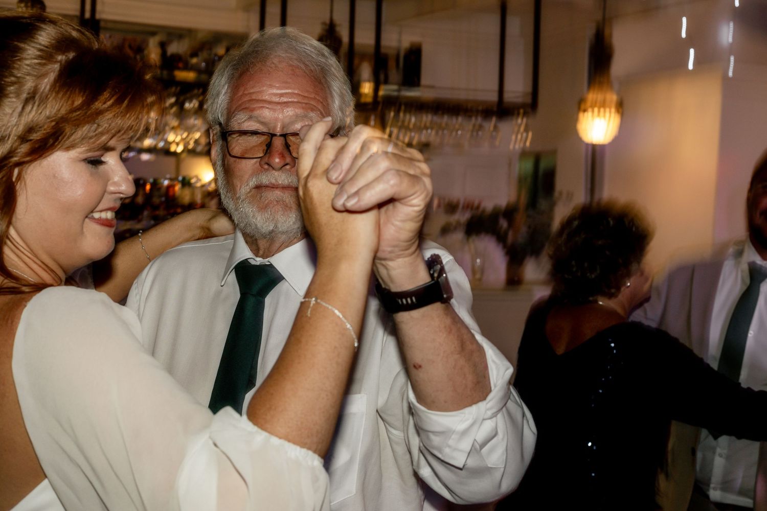 Couple sharing a joyful dance at a wedding reception in warmly lit venue.