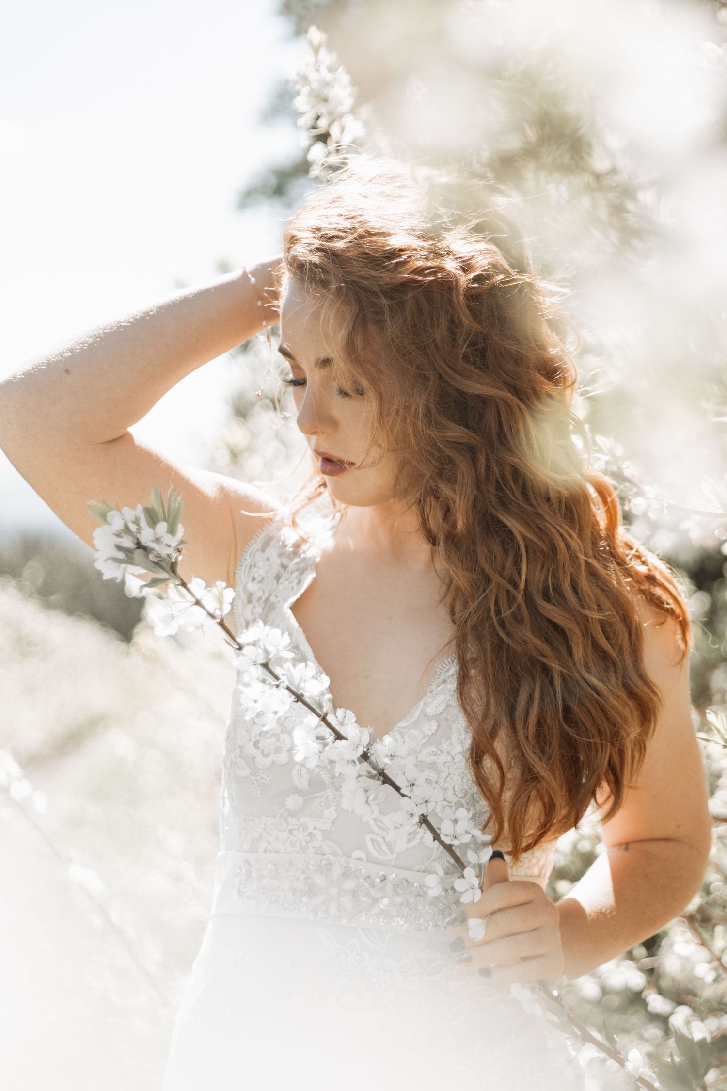 Ethereal spring portrait series with cherry blossoms glowing in soft sunlight against a dreamy white background.