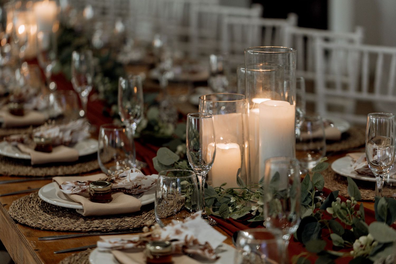 Elegant holiday table setting with silver charger plates, white candles and natural greenery garland decor.