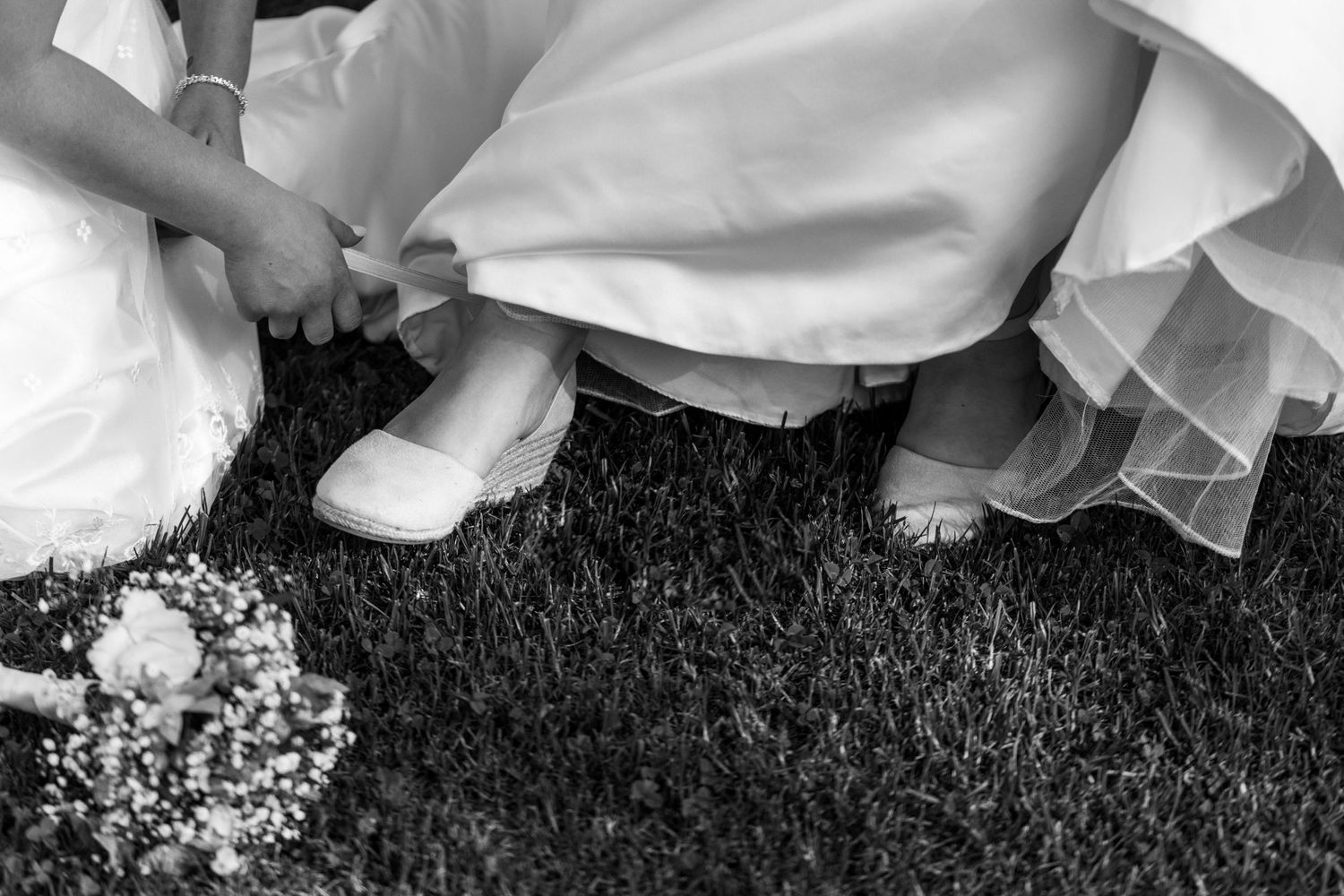 Three people wearing white shirts lying on grass with sunflowers in black and white film photography style.