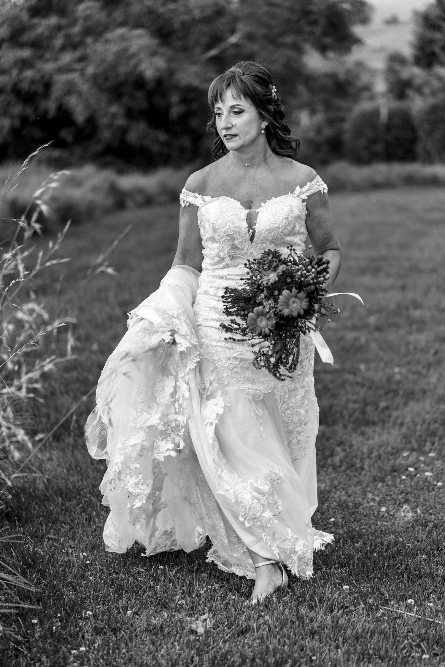 Black and white photographs show the flowing movement of a white lace wedding dress as someone runs through a grassy field.