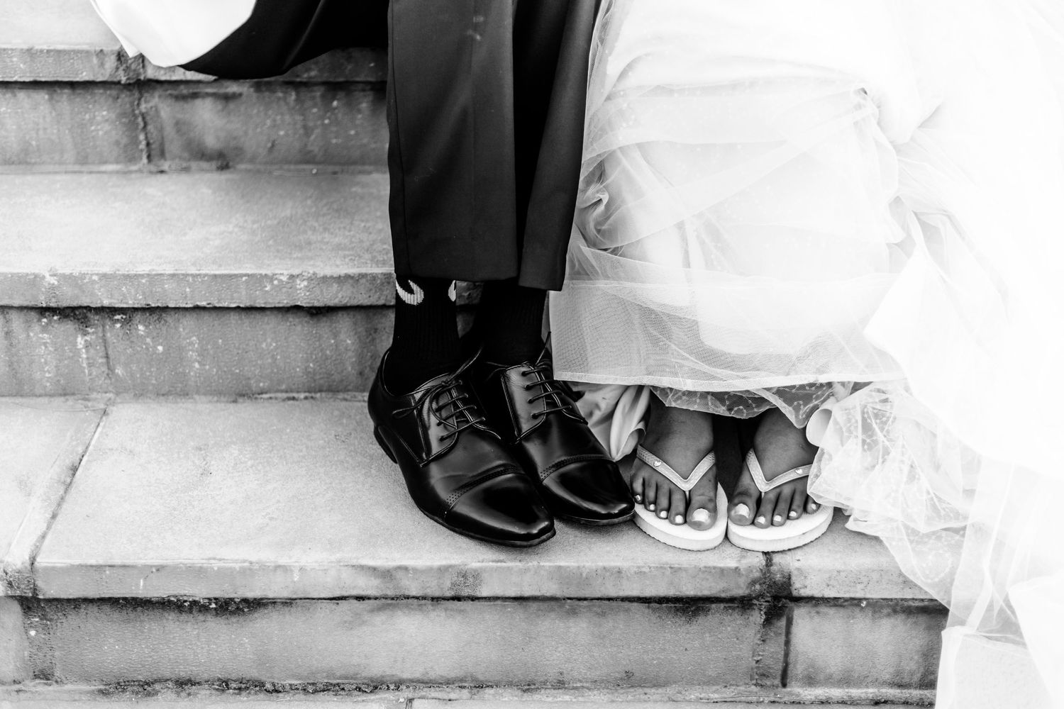 Black and white image showing dress and shoes detail on concrete steps.