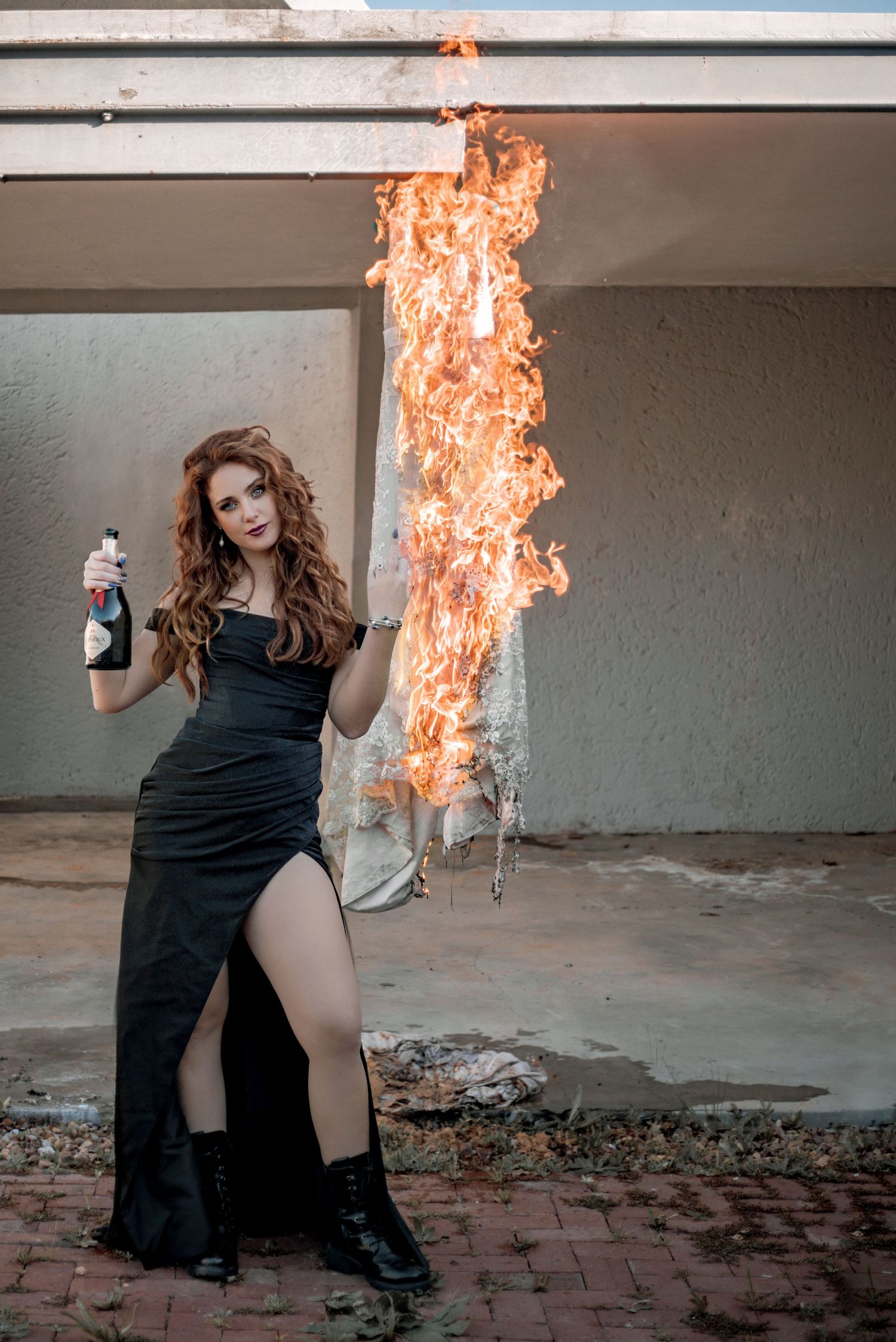 Person in black dress performing artistic fire illusion sequence in abandoned warehouse setting.