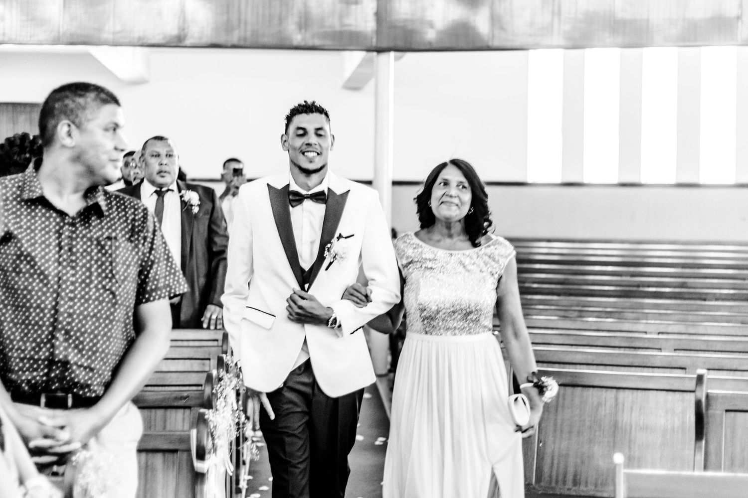 A joyful wedding couple walks down the aisle after their ceremony in this black and white photograph.