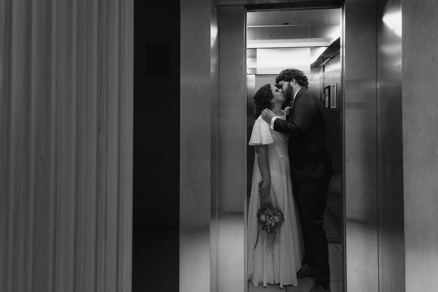 Black and white photo of a romantic couple sharing an intimate moment in an elevator.