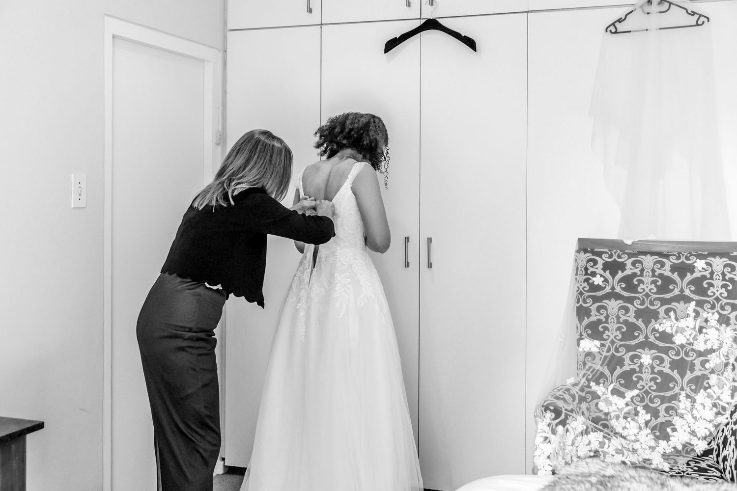 A row of white wedding dresses hanging on padded hangers against a light colored wall.