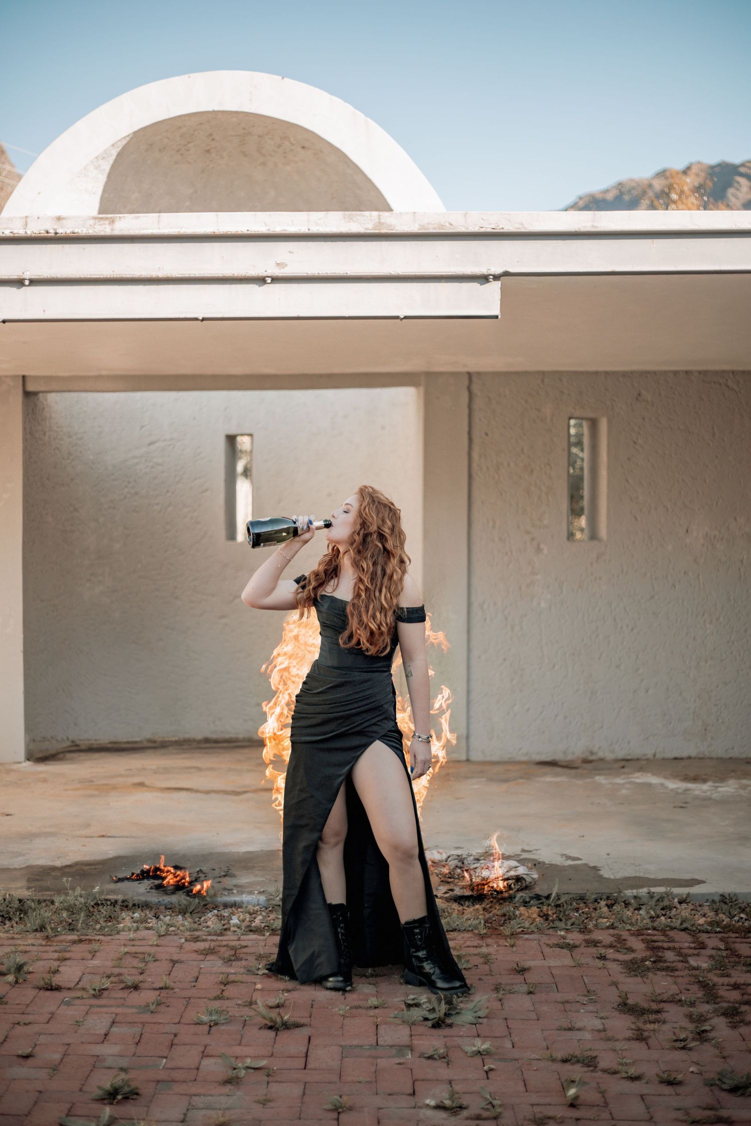 A sequence of action shots shows a person in black performing with fire on a stone patio at sunset.