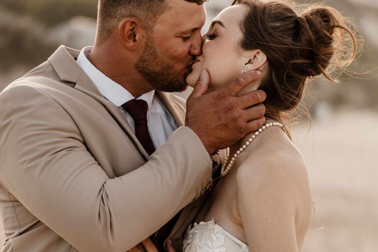 Romantic couple sharing a tender kiss in tan and beige tones during a dreamy outdoor photo session.