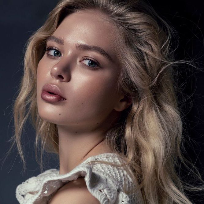 Close-up beauty portrait showcasing luminous makeup and tousled blonde hair.