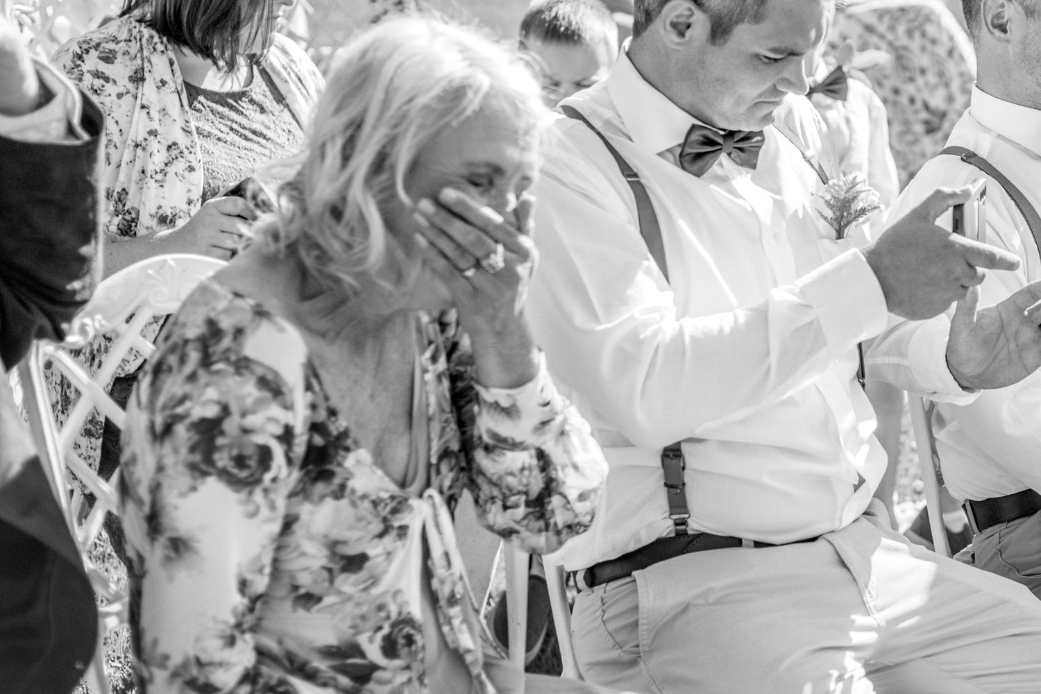 Two guests laugh together during an intimate wedding ceremony captured in black and white photography.