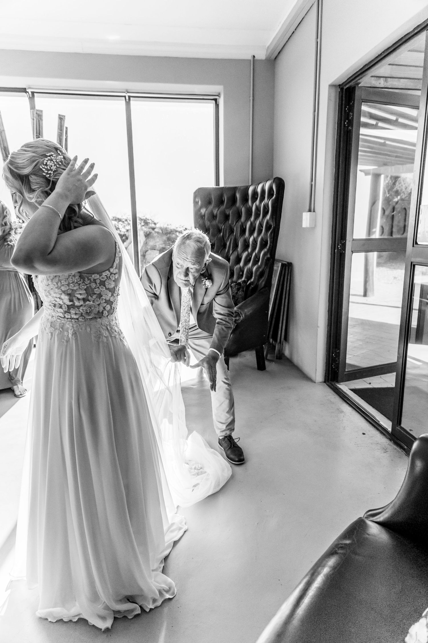 Wedding dress train stretches down a bright hallway, creating an elegant path of flowing white fabric before a special occasion.