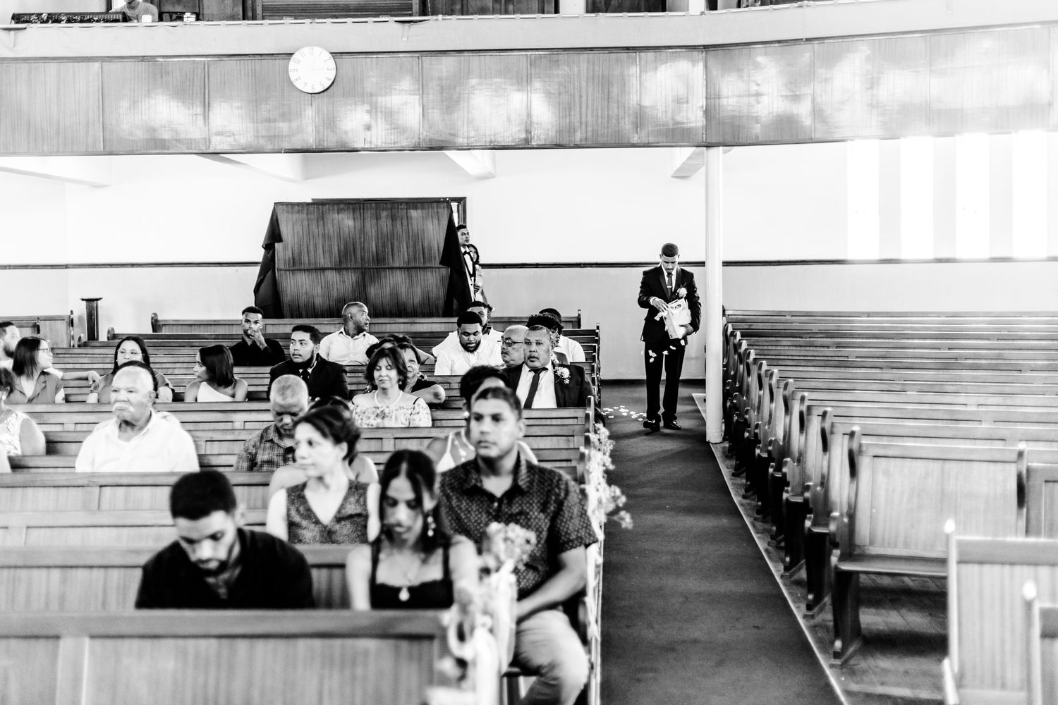 Black and white photograph showing students seated in wooden pews inside what appears to be a church or chapel interior.