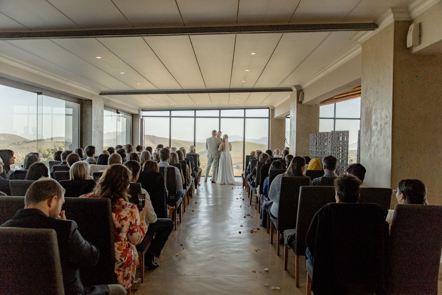 A panoramic view of a crowded business event in a modern office space with floor-to-ceiling windows and natural lighting.
