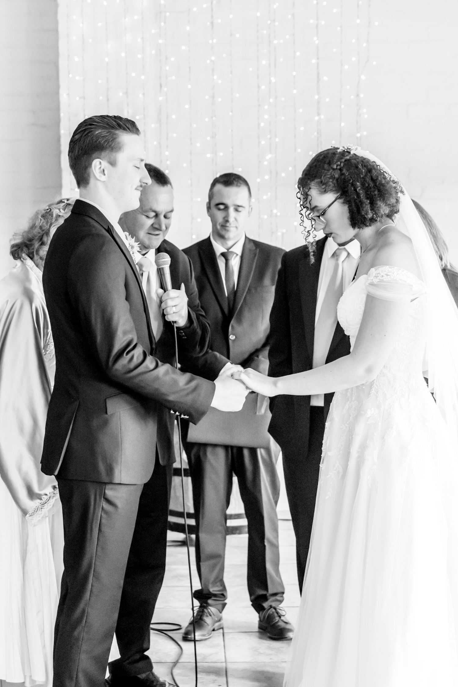 Wedding party guests in formal attire lined up in black and white against a white backdrop during reception celebration.