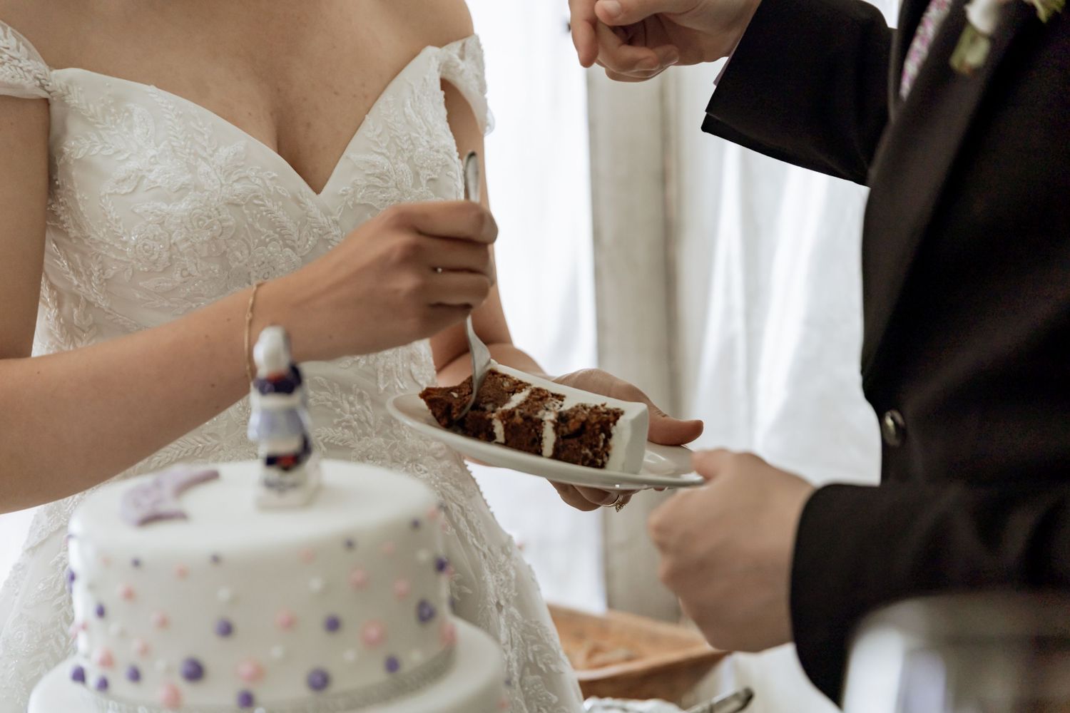 A couple cutting into their elegant three-tiered wedding cake during their wedding reception.