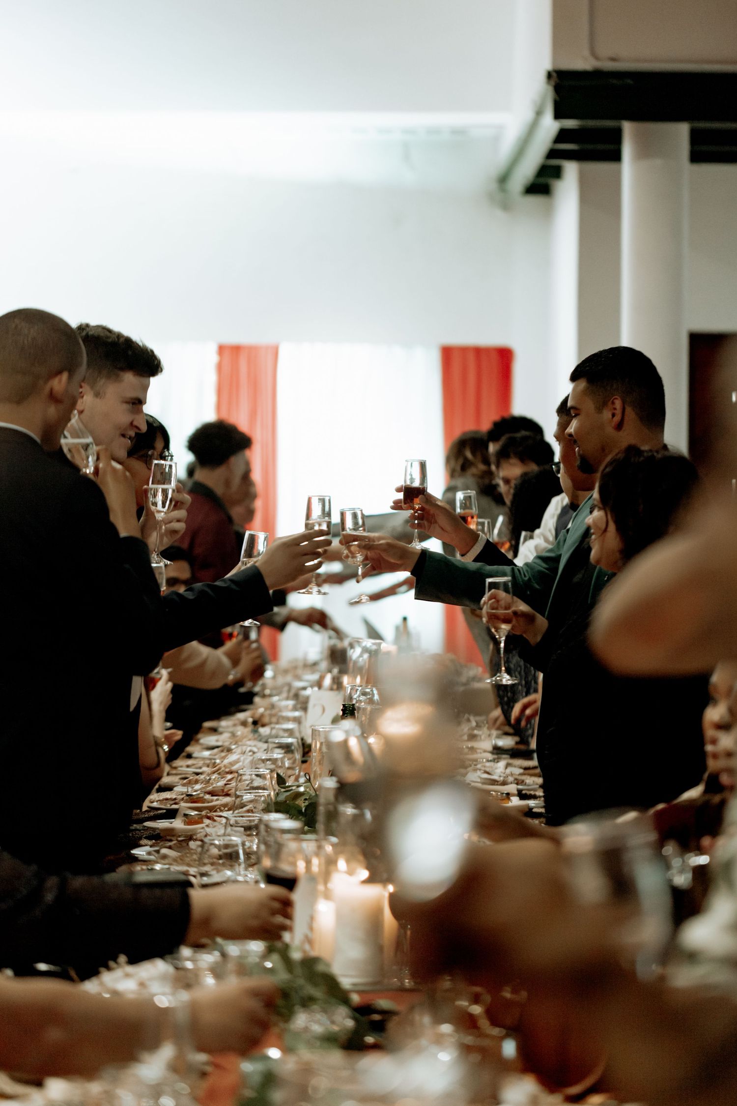 A group of people seated at a long dining table with wine glasses in a dimly lit elegant restaurant setting.