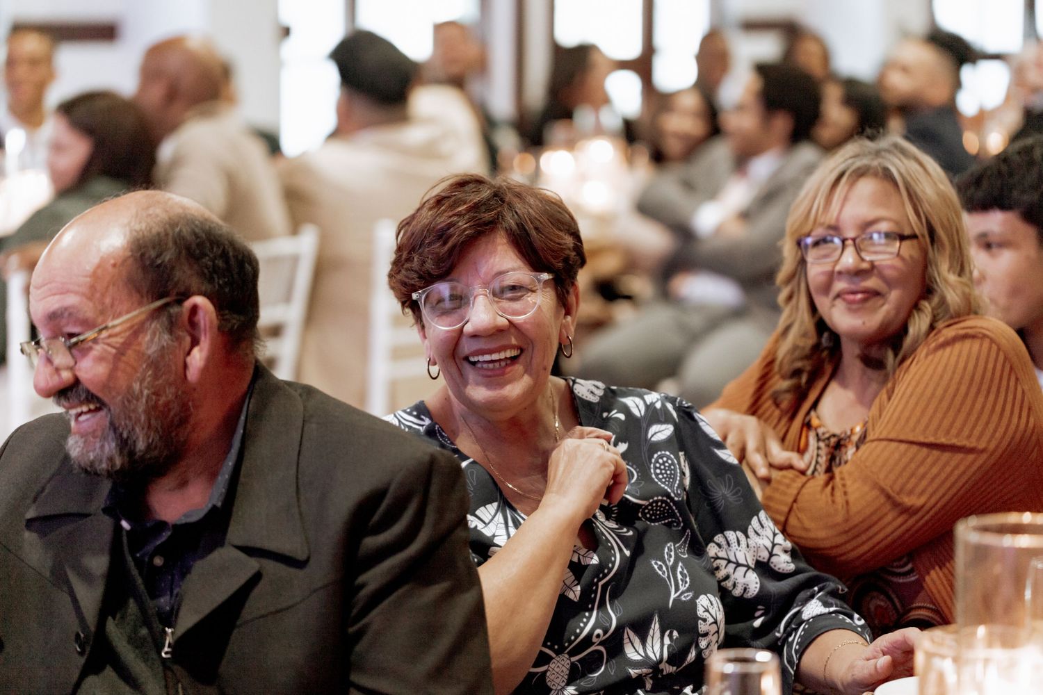 A series of candid black and white photos showing people laughing and smiling at what appears to be a social gathering.