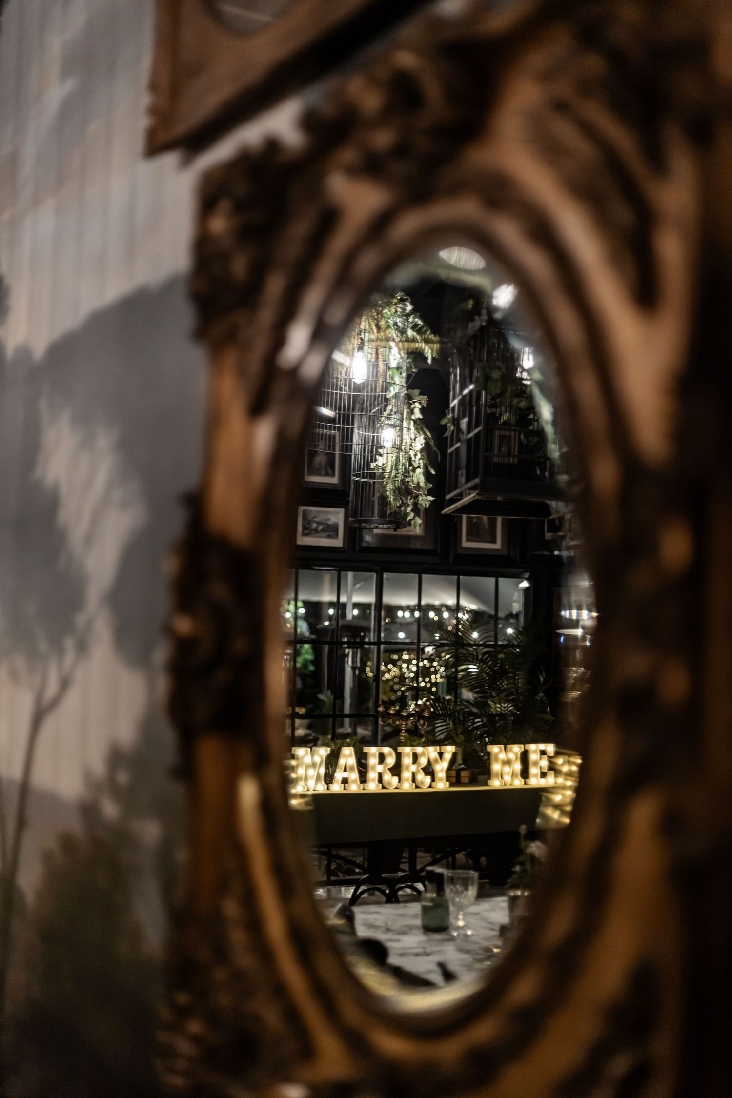Ornate gold mirror reflection shows illuminated 'Harry's' restaurant sign and interior decor at night.