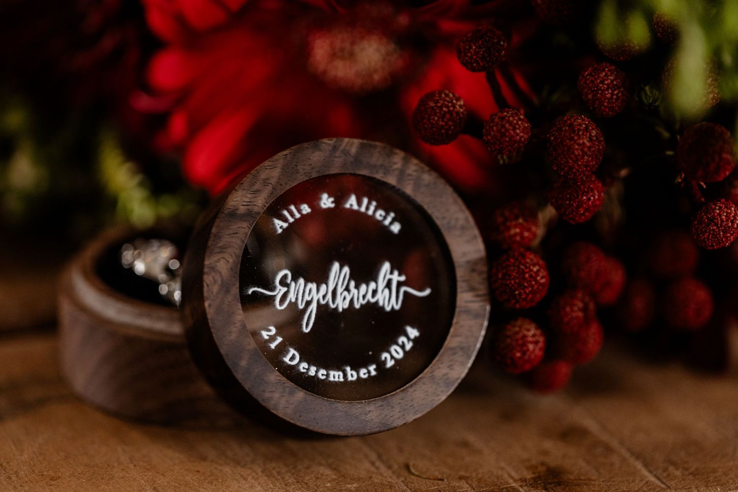Custom wooden ring box with script calligraphy text showing a couple's wedding date against dark wood background.