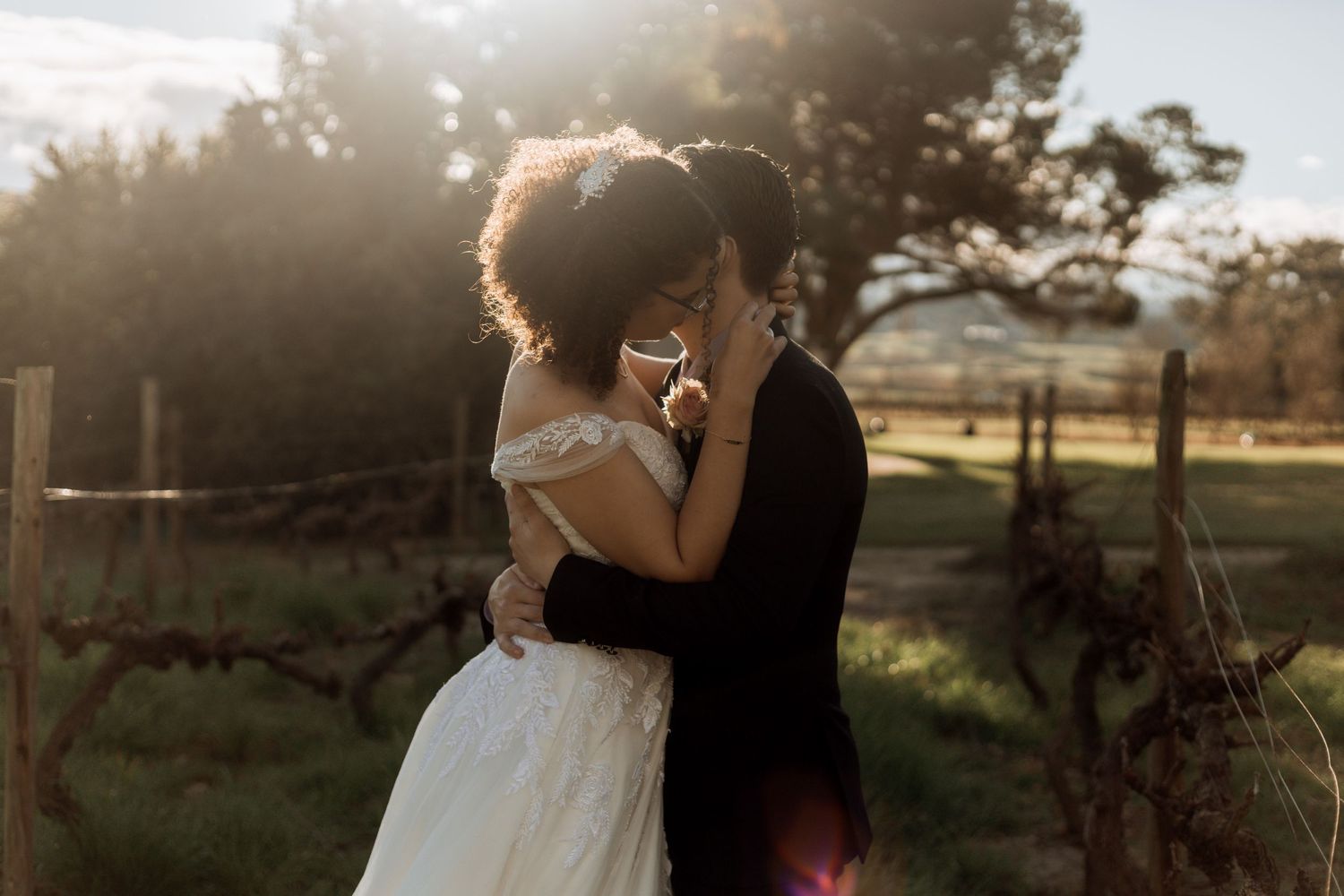 Silhouetted couple embraces in a romantic pose during golden hour sunset outdoors.