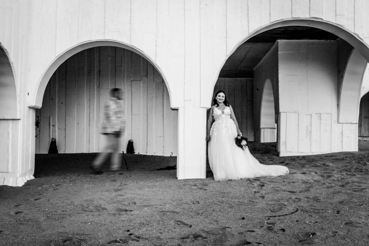 Panoramic black and white architectural image showing a series of arched corridors with dramatic shadows and light.