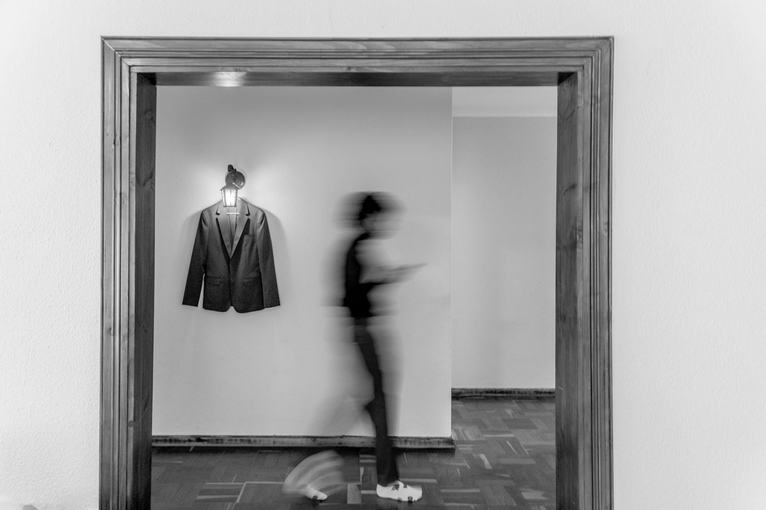 Black and white photo series showing motion blur of a person moving through doorways and spaces in an interior setting.