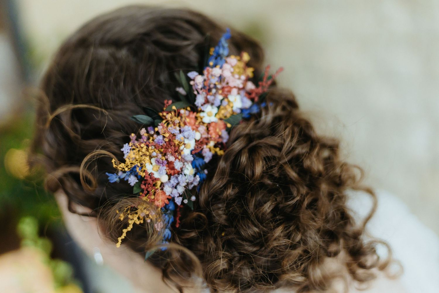 Close-up view of dark curly hair adorned with delicate floral and crystal hair accessories in a romantic style.