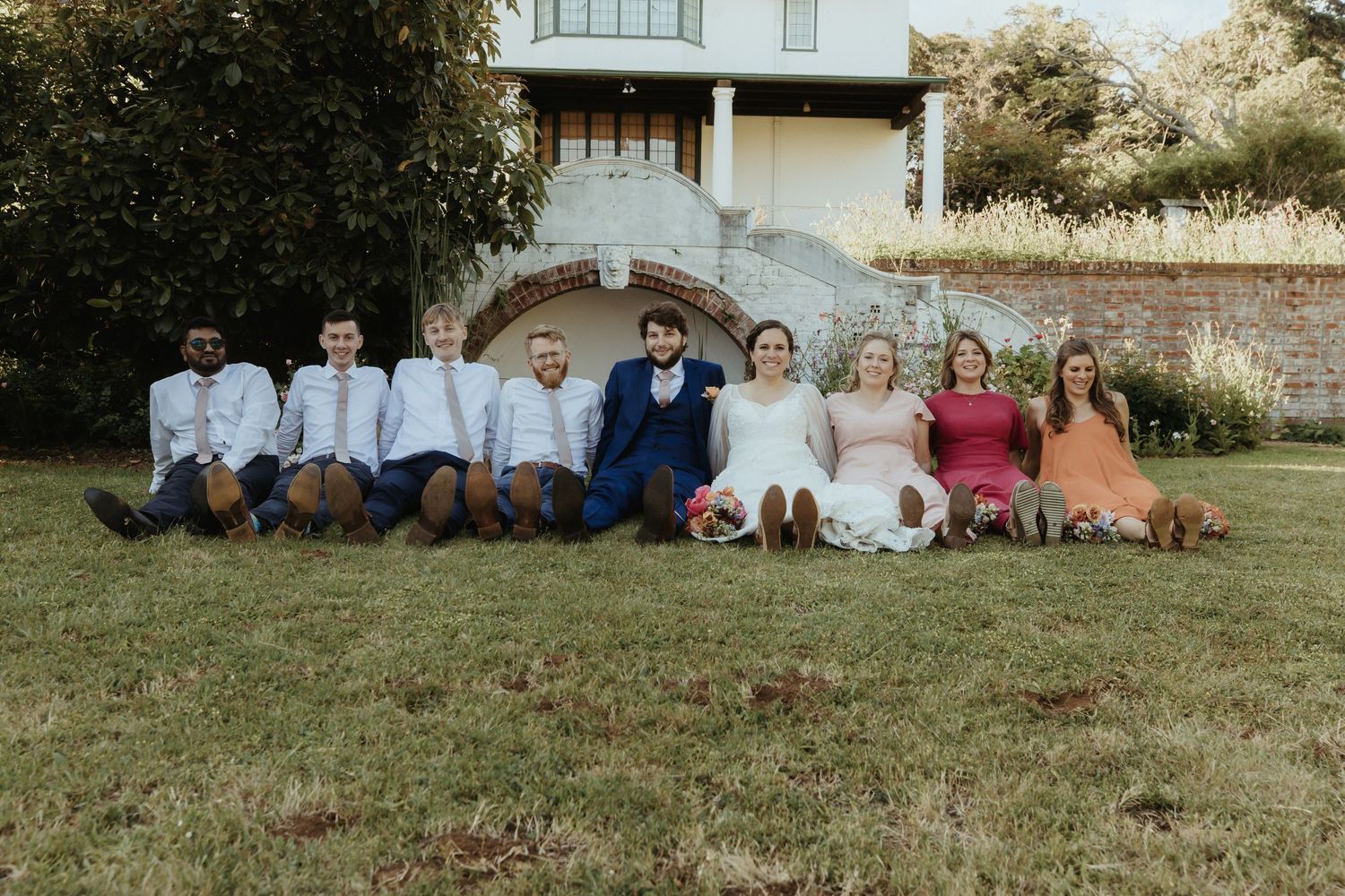 A group sits together on a grassy slope during a sunny outdoor photo session.
