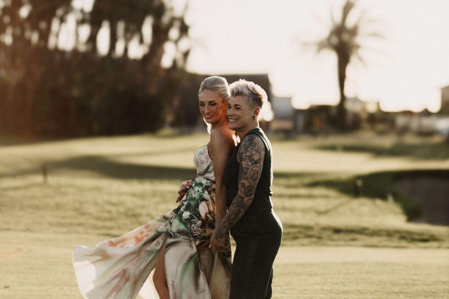 Romantic wedding couple embraces outdoors at sunset during their special day in a scenic garden setting.